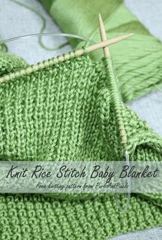 a close up of a green knitted blanket with two knitting needles in the middle