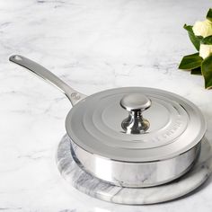 a marbled counter top with a silver pot and saucer on it next to flowers