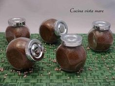 four jars with lids are sitting on a green mat and some beads are scattered around them