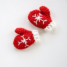 two crocheted red and white mittens with snowflakes on the top