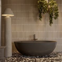 a bathtub sitting in the middle of a room next to a lamp and plant