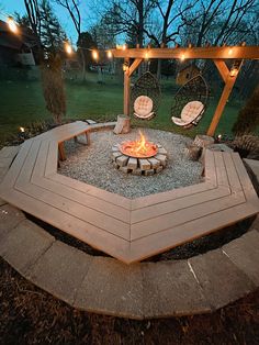 an outdoor fire pit with chairs and lights on the top, surrounded by gravel area