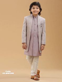 a young boy wearing a purple outfit and white pants, standing in front of a beige background