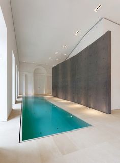 an indoor swimming pool in the middle of a room with white walls and flooring