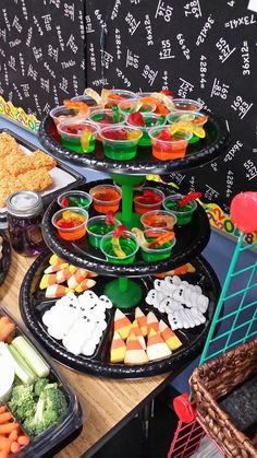 several trays of food are arranged on a table in front of a chalkboard