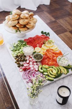 an assortment of vegetables and crackers on a marble platter next to a glass of orange juice