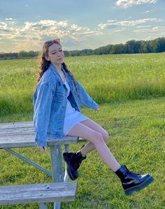 a young woman sitting on top of a wooden bench