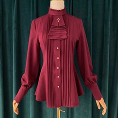 A pleated blouse that looks like an aristocratic lady from medieval Europe. It has a pleated chest and a removable cravat decorated with a cross. The cuffs are long and the waist is tapered. For a young lady with a noble atmosphere. 
 
 

 

 
 
 Color 
 
 Black 
 White 
 Red 
 Light brown 
 
 
 Size 
 
 
 S size 
 
 Length: 63-68cm 
 Shoulder width: 36cm 
 Bust: 86cm 
 Waist: 70cm 
 Sleeve length: 60cm 
 
 M size 
 
 Length: 64-69cm 
 Shoulder width: 37.5cm 
 Bust: 92cm 
 Waist: 76cm 
 Sleeve l Gothic Formal Tops For Fall, Formal Gothic Long Sleeve Blouse, Gothic Long Sleeve Blouse For Evening, Long Sleeve Gothic Blouse For Formal Occasions, Gothic Formal Tops With Ruffles, Formal Pleated Long Sleeve Blouse, Formal Long Sleeve Pleated Blouse, Fitted Pleated Blouse For Formal Occasions, Elegant Winter Tops With Ruffled Collar