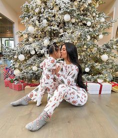 a mother and daughter sitting in front of a christmas tree