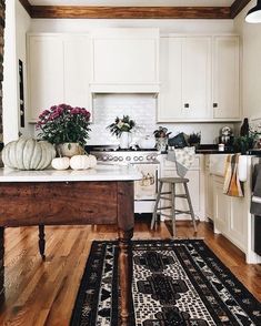 a kitchen with white cabinets and an area rug in front of the stove top oven