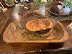 an old wooden bowl sitting on top of a table next to other bowls and vases