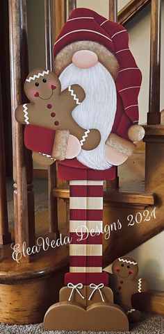 a santa clause holding a teddy bear on top of a stair case next to some gingerbreads