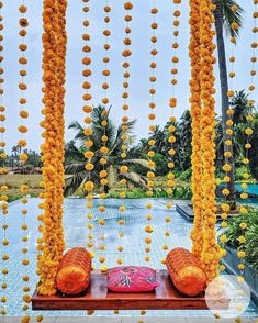 an outdoor area with yellow flowers hanging from the ceiling and pillows on the ground in front of it