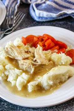 a white plate topped with meat and veggies covered in gravy next to a fork