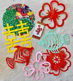 paper cutouts are laid out on a white tablecloth with chinese characters and flowers