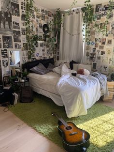 a bed room with a guitar on the floor next to a wall covered in pictures