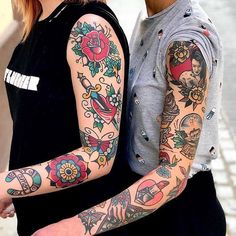 two people standing next to each other with tattoos on their arms