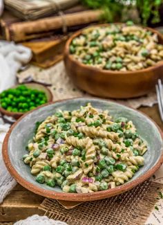 a bowl filled with pasta and peas on top of a table next to other dishes