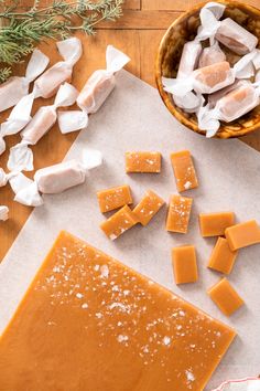 several pieces of cheese are on a cutting board next to some marshmallows