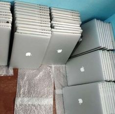 several apple laptops are sitting on the floor in front of some plastic wrappers