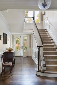 an entry way with stairs and chairs in the hallway leading up to the front door