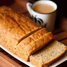 a loaf of bread sitting on top of a white plate next to a cup of coffee