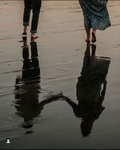 two people walking on the beach holding umbrellas