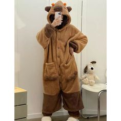 a person in a brown bear costume taking a selfie with a cell phone while standing next to a chair