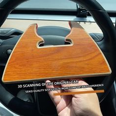 someone is holding up a wooden object in their car's steering wheel rim holder