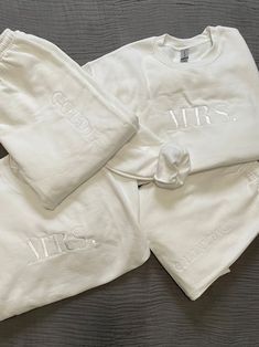 three white sweatshirts with mr and mrs embroidered on them sitting on top of a bed