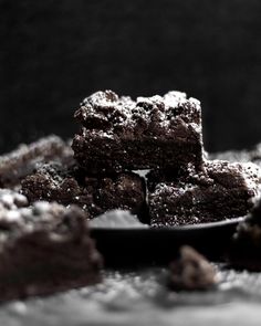 some brownies are on a plate with powdered sugar and chocolate chips around them