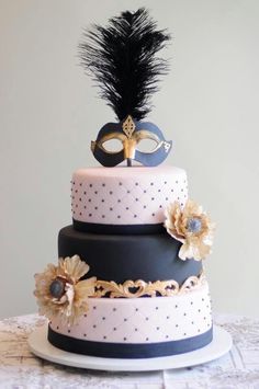 a three tiered cake with a masquerade on top and flowers in the middle