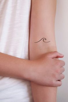 a woman's arm with a small wave tattoo on the left side of her arm