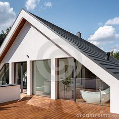 a white house with a wooden deck and glass doors leading to the outside bathtub