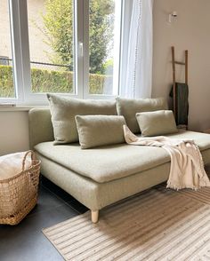 a living room with a couch, rug and window overlooking the yard in front of it