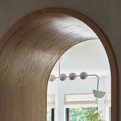 an arched wooden door leading to a living room with white walls and furniture in the background