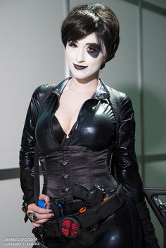 a woman dressed in black leather with makeup on her face