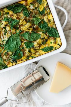 a casserole dish with spinach and cheese in it next to a slice of cheese