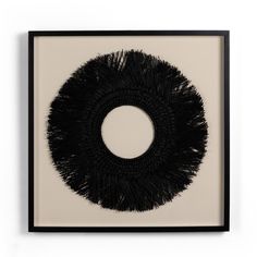 a black and white painting with a circular design on it's side, in a frame