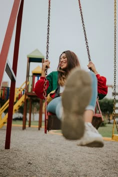 a woman sitting on a swing in a playground