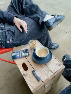 a person sitting on a red chair next to a cup of coffee and cell phone