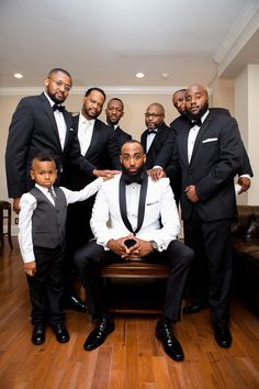 a group of men in tuxedos posing for a photo together on a wooden floor