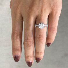 a woman's hand with a diamond ring on her left hand and the other hand holding an engagement ring