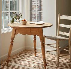 a small wooden table in front of a window with a book on top of it