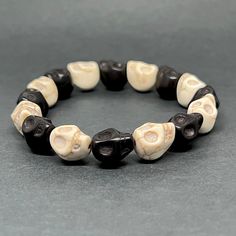 Experience the bold and unique style with this striking Skull Beaded Wristband Bracelet. The alternating black and white beads add a touch of contrast to this Day of the Dead inspired jewelry that is perfect for anyone. Show your passion for fashion and celebrate Halloween in style with this cool accessory. Makes a great gift for him or her. ¡Consigue ya tu pulsera de calaveras y demuestra tu entusiasmo por la moda y la vida! Casual Black Bracelets For Halloween, Handmade Black Skull Bracelets, Handmade Black Skull Bracelet, Adjustable Bone-colored Bracelet, Black Round Bead Bracelets For Halloween, Black Round Beaded Bracelets For Halloween, Halloween Black Bracelets With Round Beads, Casual White Bracelet With Black Beads, Spiritual White Bracelet With Black Beads