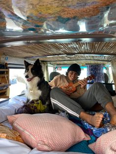 a man and his dog sitting in the back of a van with pillows on it