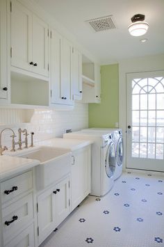 a washer and dryer in a white kitchen with blue tile on the floor