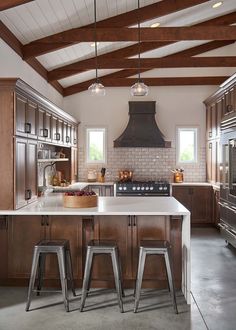 a kitchen with two stools in front of an island and range hood above it