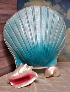 a shell shaped object sitting on top of a bed next to an open seashell