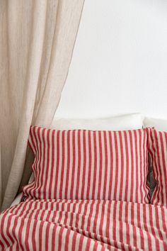 a red and white striped bed spread with two pillow cases on top of each other